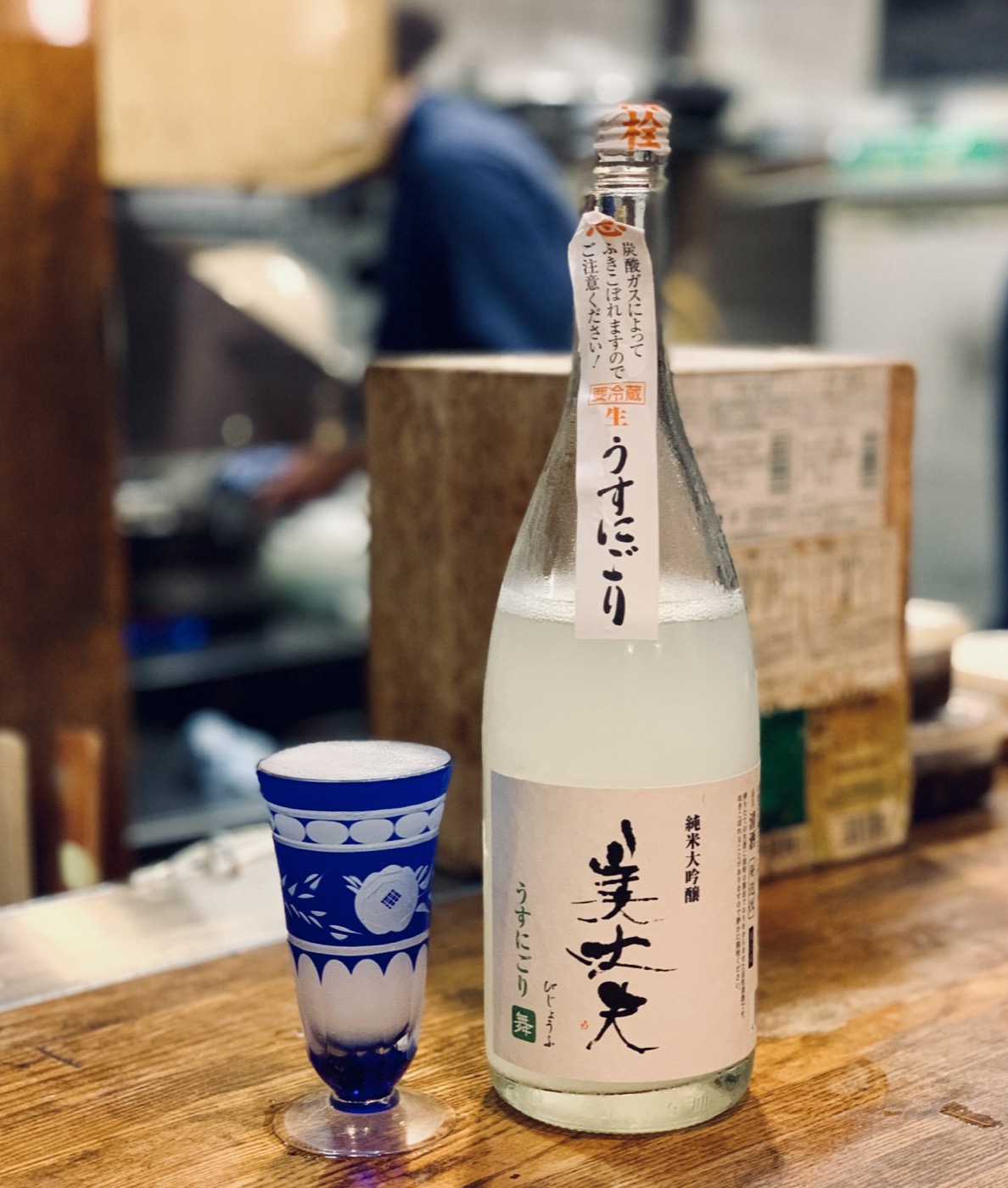 A bottle of Bijofu junmai daiginjo with a blue cut-glass cup on a counter